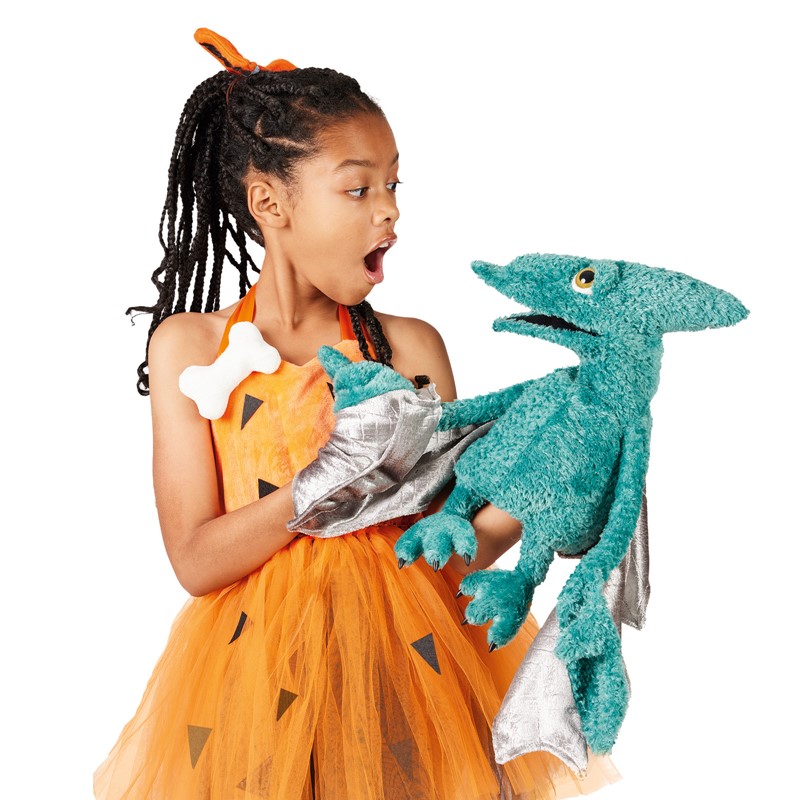 Girl in a Stone Age costume holds a teal Folkmanis pterodactyl hand puppet with silver wings, mouth open in amazement