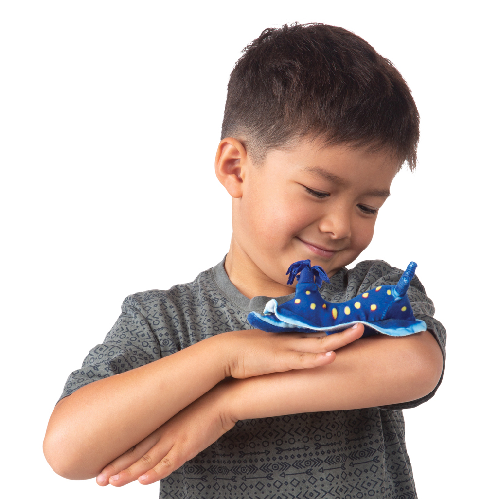 Junge hält lächelnd eine Folkmanis Fingerpuppe mini blaue Nacktkiemenschnecke in Blau mit gelben Flecken auf seinem Handrücken.