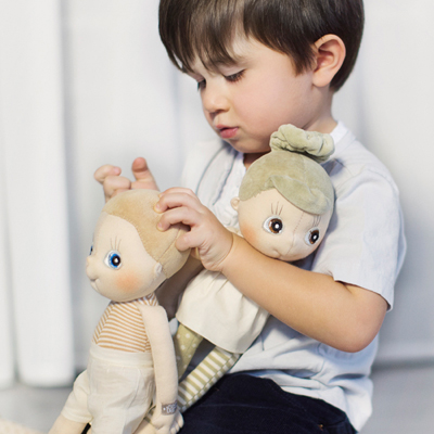 Child holding two Rubens EcoBuds dolls in their arms